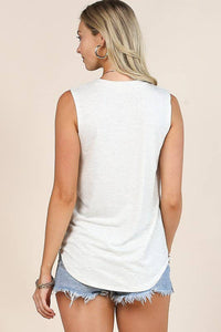 Woman wearing a white sleeveless top and denim shorts on a beige background
