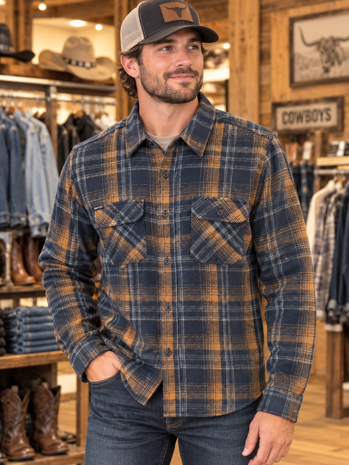 sexy man in brown and blue flannel with rust color in a store with clothes