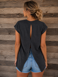 Woman wearing a black t-shirt with a cutout design on the back against a wooden wall.