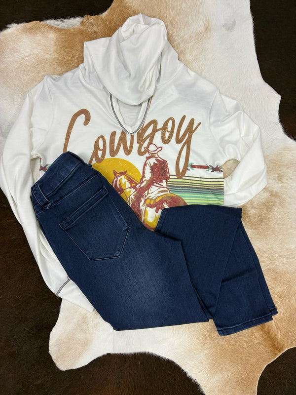 White hoodie with 'Cowboy' graphic and blue jeans on a cowhide rug
