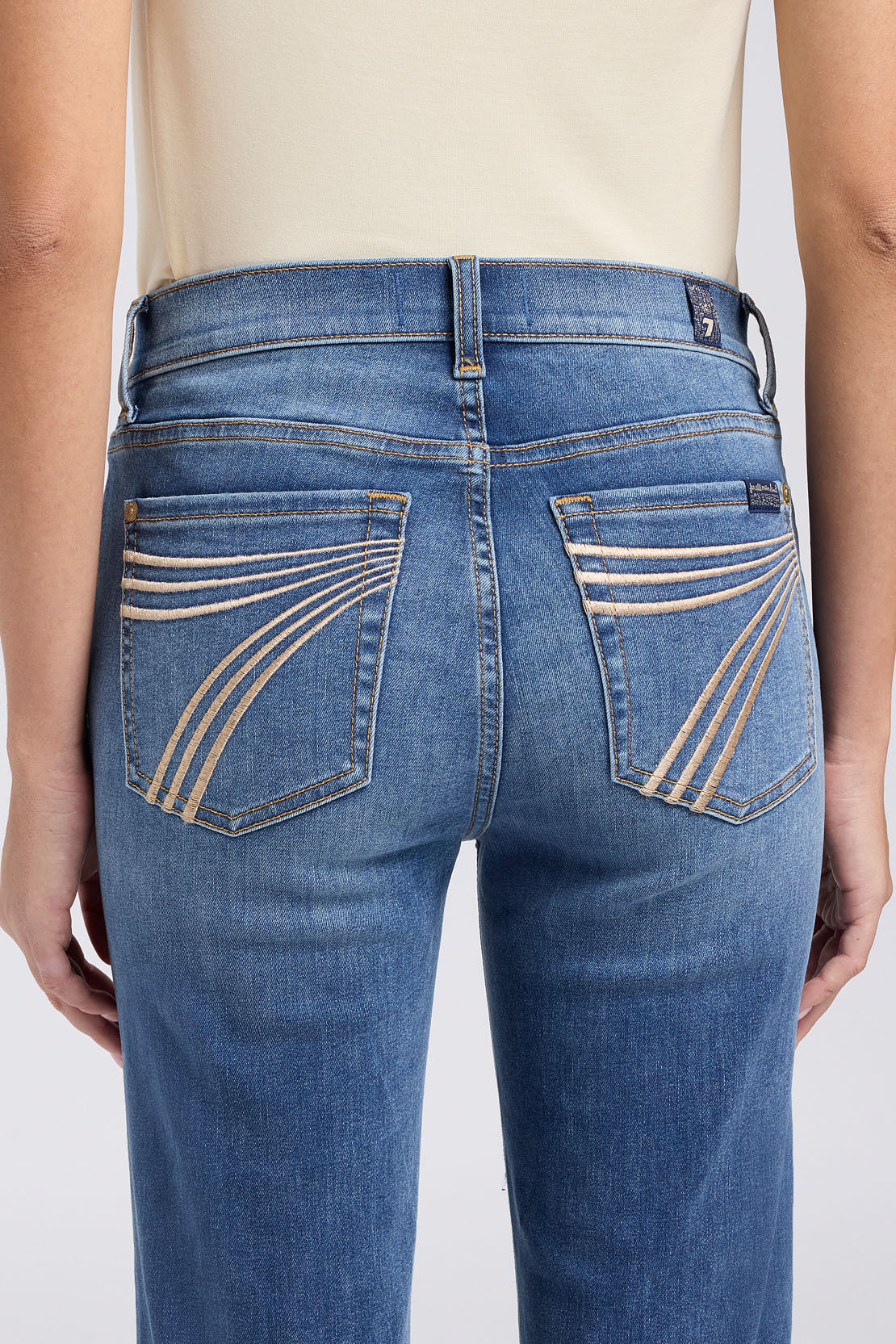 Blue jeans with decorative stitching on a plain background
