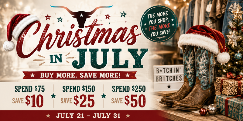A promotional holiday banner for 'Christmas in July' at 'B*Tchin Britches', featuring a bull skull, cowboy boots with Santa hats, a Christmas tree, and gift boxes on a rustic wooden surface, with text detailing savings for different spend levels.