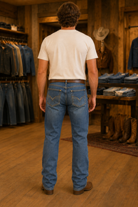 A man viewed from behind wearing a white t-shirt and blue jeans in a rustic wooden clothing store.